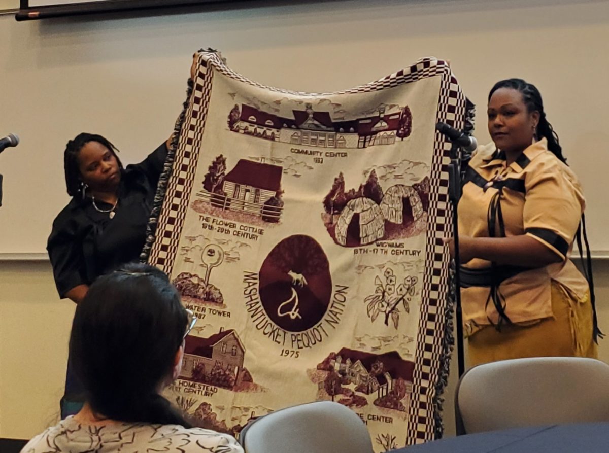 Professor Jessica Scott and her sister, Michele Scott, a tribal councilwoman for the Mashantucket Pequot Tribal Nation, present a blanket from their tribe to the university.